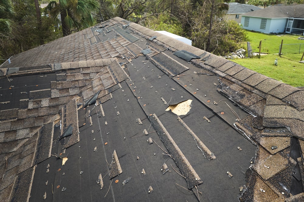 Damaged house roof with missing shingles in Southern Maryland